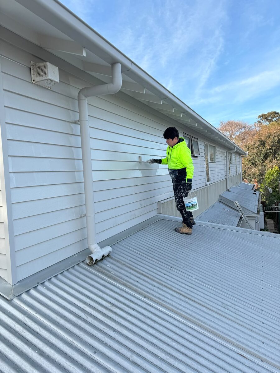 Painter coating a roof from the roof surface